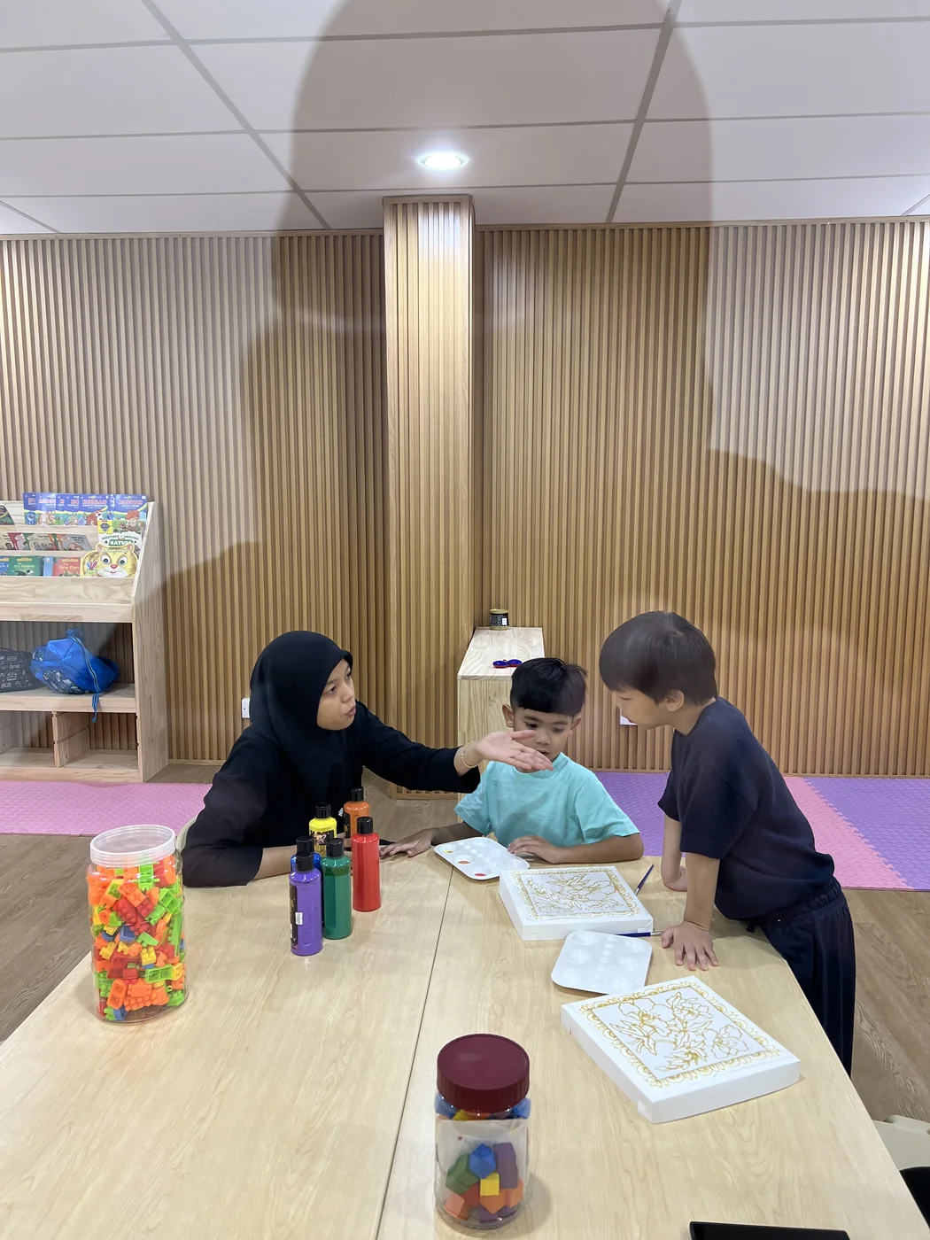 An educator supporting a learner during a creative classroom task